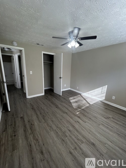 A room with a ceiling fan and wood flooring.