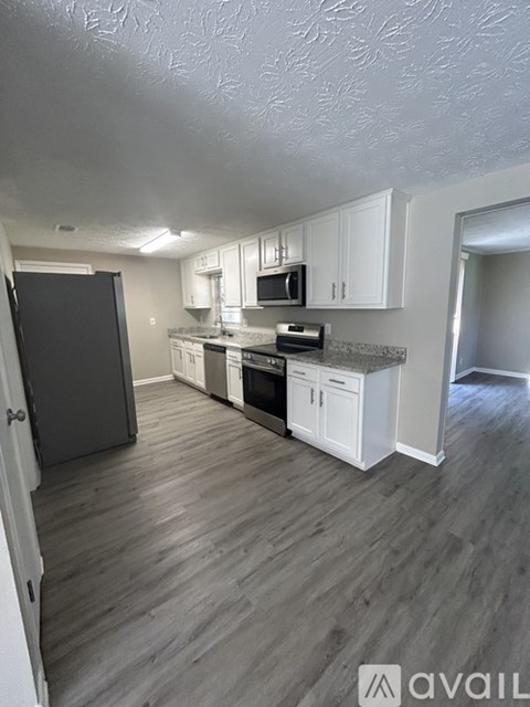 A kitchen with white cabinets and a black refrigerator.
