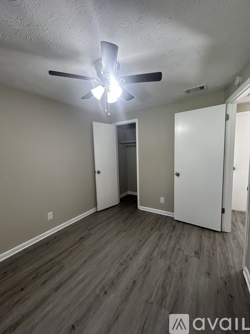 A room with a ceiling fan and light, and two doors, one of which is open.