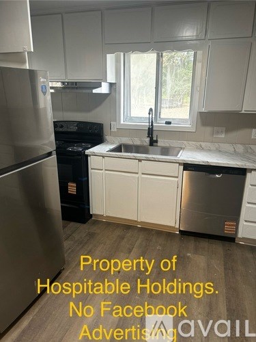A kitchen with a refrigerator, stove, and dishwasher, with a window above the sink.