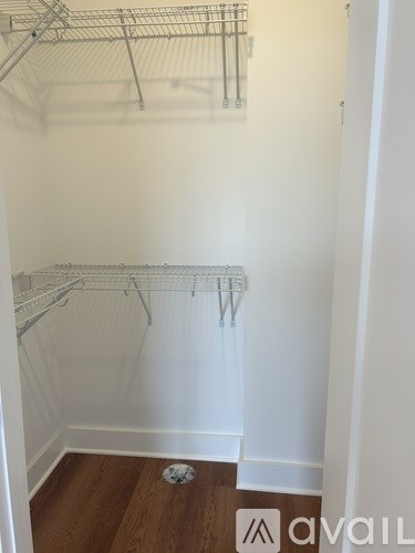 A white closet with a wooden floor and a white door.