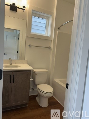 A bathroom with a toilet, sink, and window.