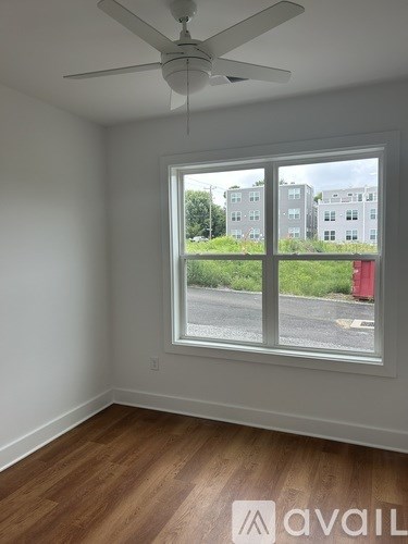A room with a ceiling fan and a window overlooking a street.