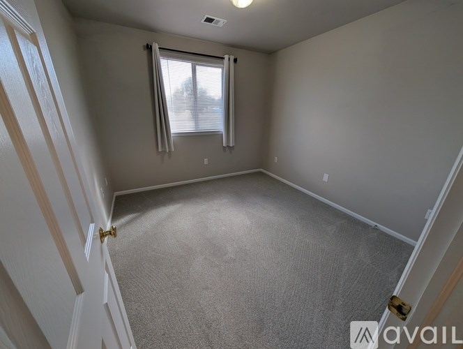 A carpeted room with a window and a door.
