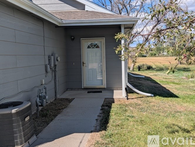 A house with a grey siding and a white door is for sale.
