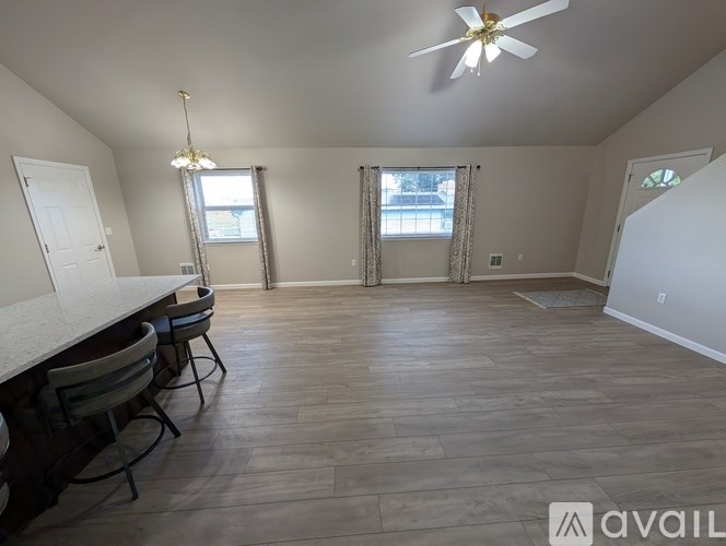 A room with a ceiling fan and a table with chairs.