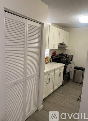 A kitchen with white cabinets and a black countertop.