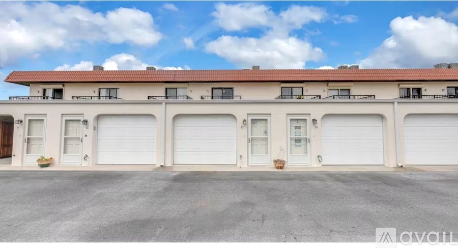 A building with a red roof and white walls has multiple garage doors.