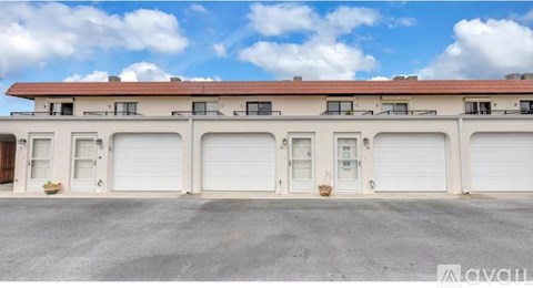 A building with a red roof and white walls has multiple garage doors.