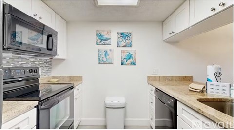 A kitchen with white cabinets and a black stove top oven.