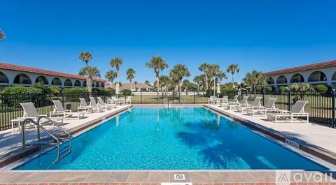 A large swimming pool surrounded by lounge chairs and palm trees.