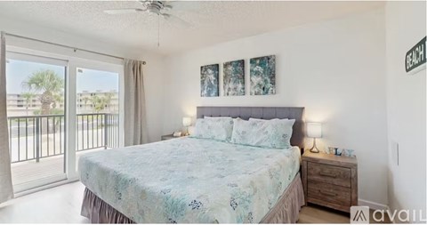 A bedroom with a large bed and a balcony with a view of the beach.