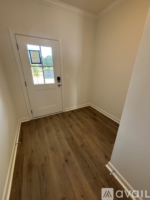 A room with a white door and a window showing trees outside.