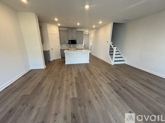 A spacious room with wooden flooring and a staircase leading to another level.