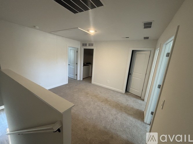 A spacious room with a carpeted floor and white walls.