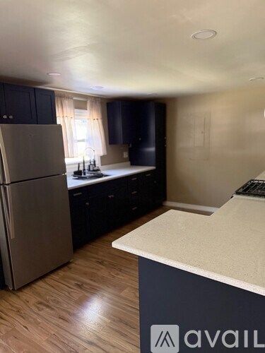 A kitchen with a refrigerator, cabinets, and a countertop.