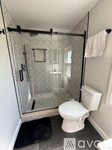 A white toilet is in a bathroom with a glass shower door.