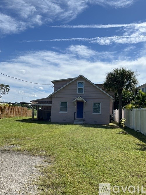 A house with a blue door is surrounded by a white fence.