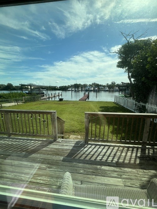 A view from a window looking out to a dock with a boat and a fence.