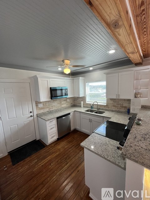 A kitchen with a wooden ceiling and a granite countertop.