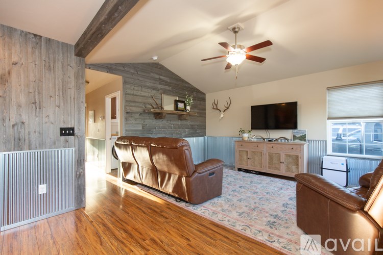A living room with a brown leather couch and a wooden floor.
