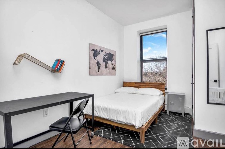 A bedroom with a bed, chair, and a world map on the wall.