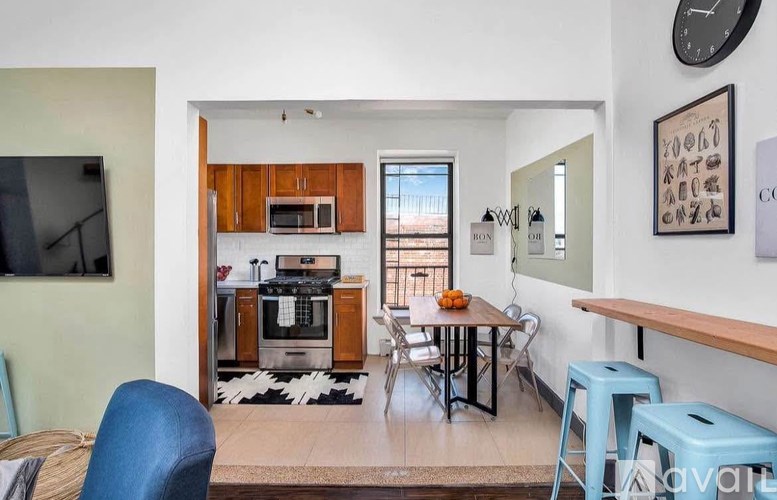 A living room with a blue chair and a television on the wall.