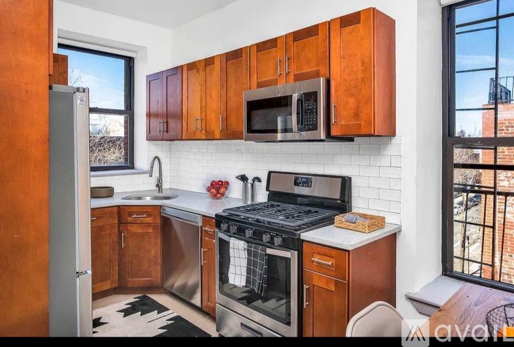 A kitchen with wooden cabinets and a black and white rug.
