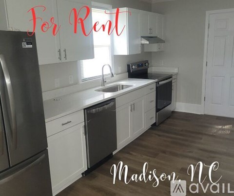 A kitchen for rent with white cabinets and stainless steel appliances.