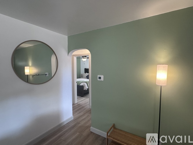 A room with a round mirror on the wall and a lamp on the floor.