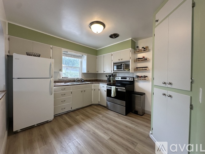 A kitchen with white appliances and wooden floors.