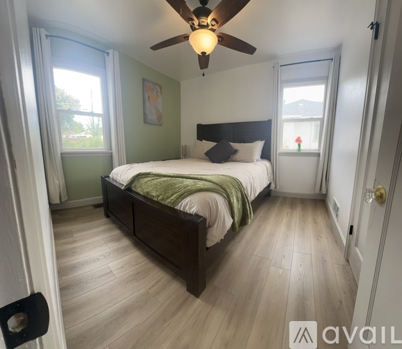 A bedroom with a bed, a ceiling fan, and a door.