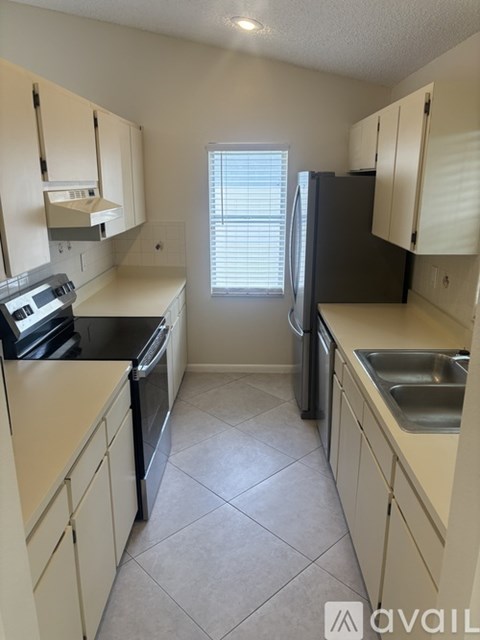 A kitchen with white cabinets and a black refrigerator.