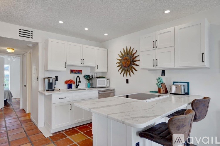 A kitchen with white cabinets and a marble countertop.