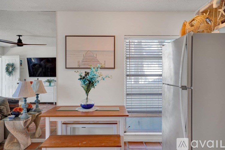 A living room with a white refrigerator and a painting on the wall.