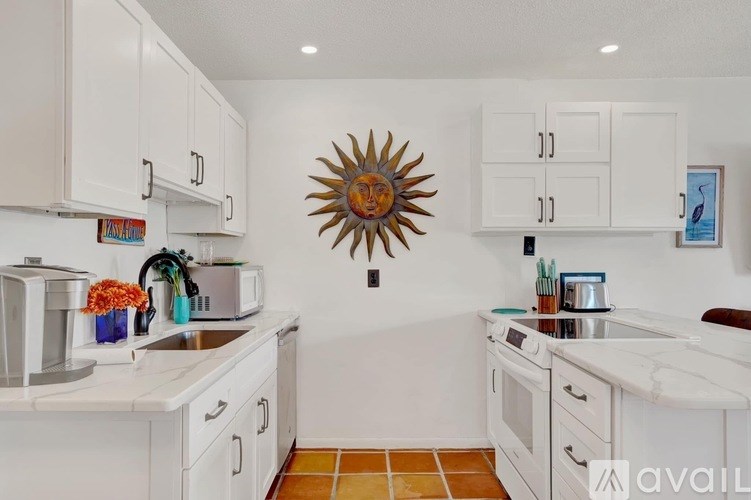 A kitchen with white cabinets and a sunflower decoration on the wall.