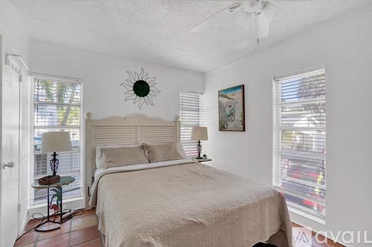 A bedroom with a bed, two lamps, and a ceiling fan.