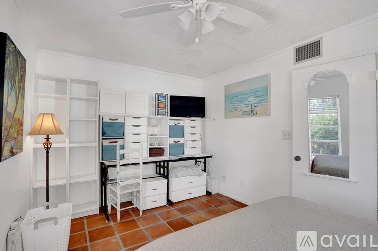A room with a desk, chairs, and a fan.