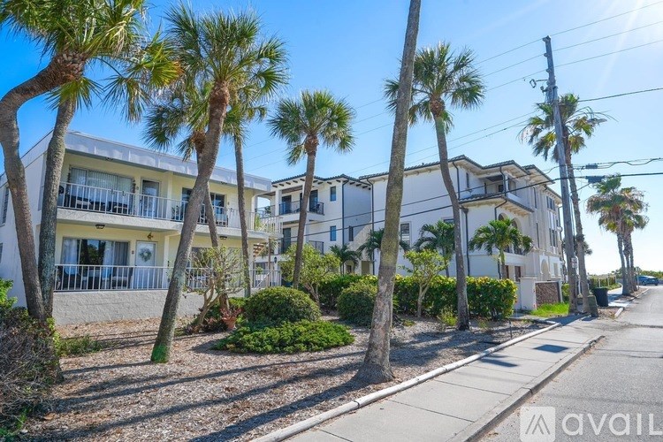 A row of houses with palm trees in front.