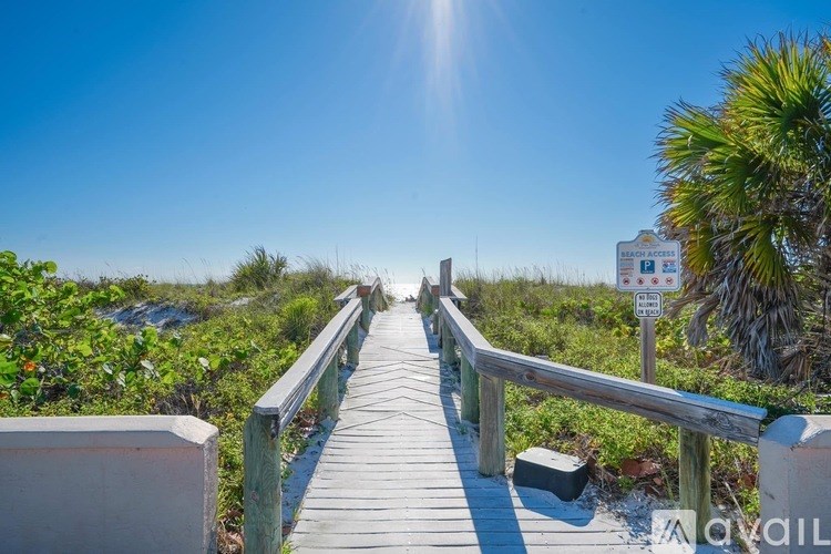 A wooden boardwalk leads through a natural area with a sign on the right.