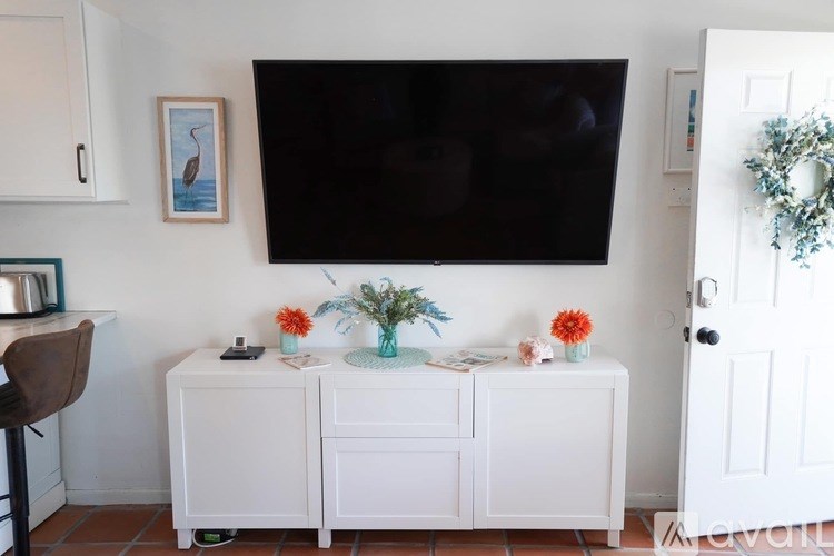 A white cabinet with a flat screen TV mounted above it.
