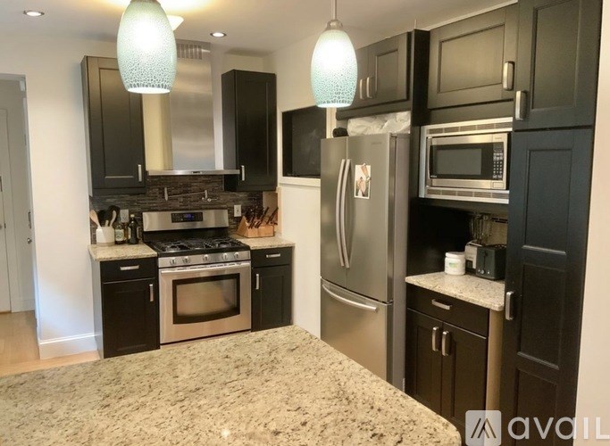 A kitchen with black cabinets and stainless steel appliances.