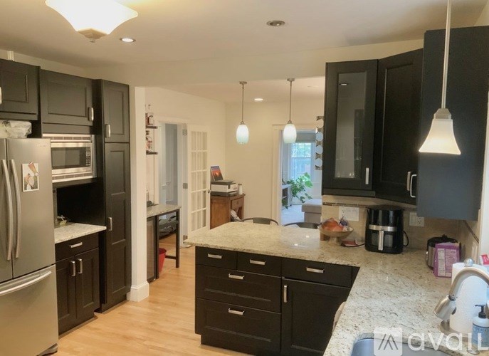 A kitchen with black cabinets and a marble countertop.
