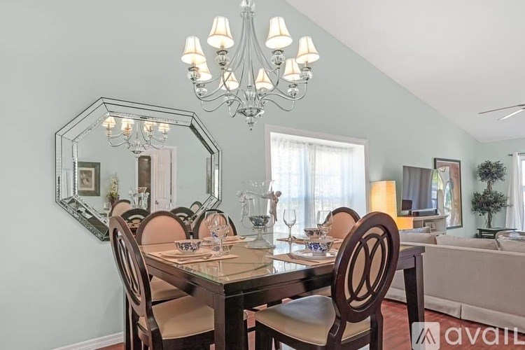 A dining room with a table set for six and a chandelier.