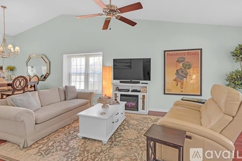 A living room with a beige couch, a white coffee table, and a painting on the wall.