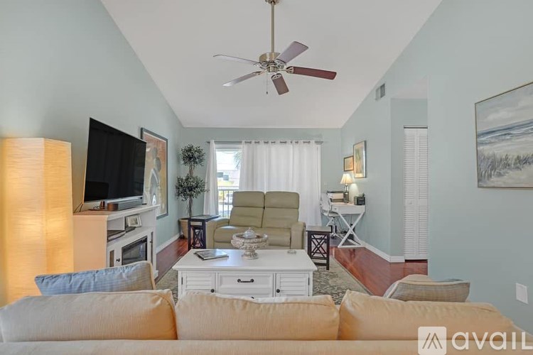A living room with a beige couch and a ceiling fan.