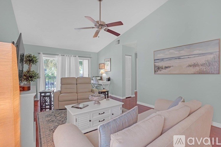 A living room with a fan, a couch, and a painting on the wall.