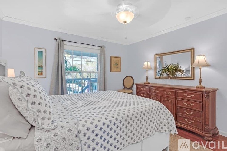 A bedroom with a large bed and a wooden dresser.