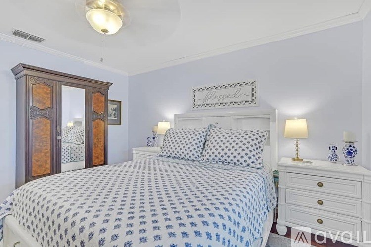 A bedroom with a bed, nightstand, and a wooden cabinet.