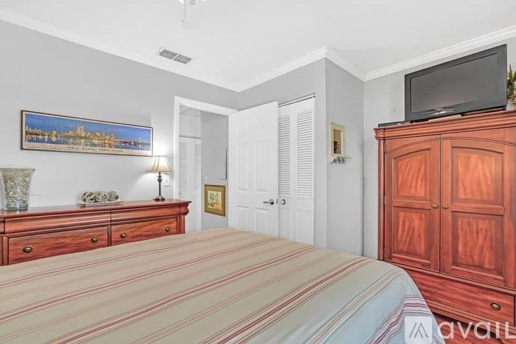 A bedroom with a bed, dresser, and a painting on the wall.